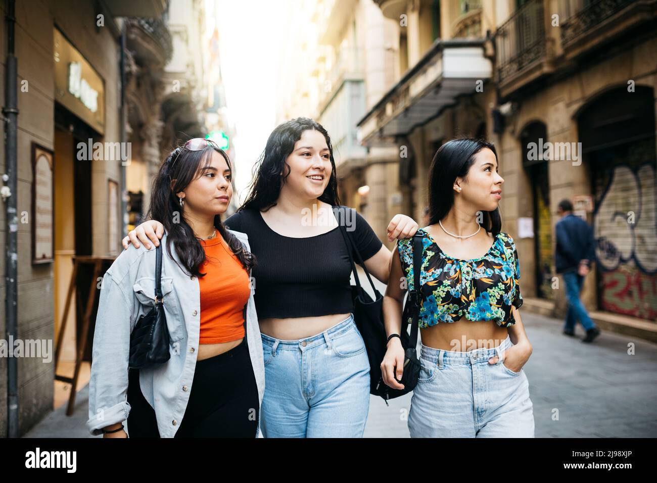 Tres mujeres jóvenes caminando y pasando el rato en una calle comercial de una gran ciudad Foto de stock