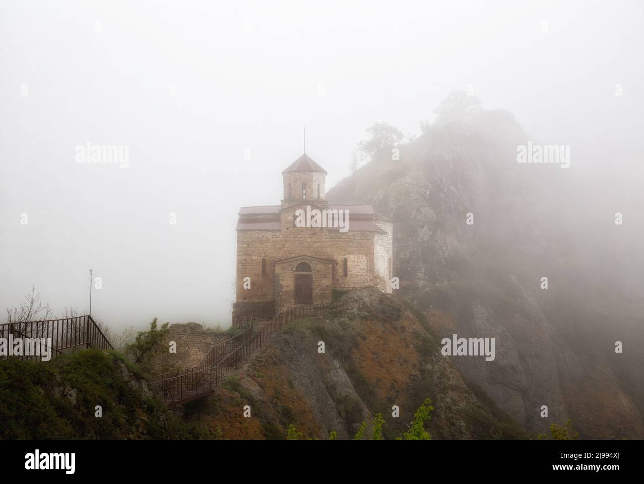 Antigua iglesia Shoana del siglo 10th en la cima de una cadena montañosa en densa niebla Foto de stock