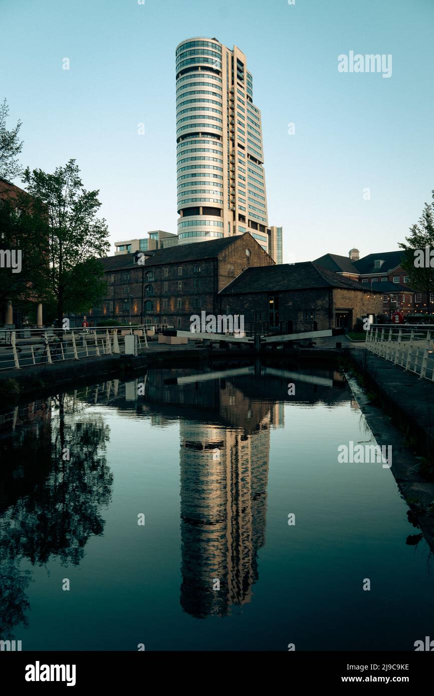 El rascacielos Bridgewater Place en Leeds se refleja en el agua del canal de Granary Wharf al atardecer Foto de stock