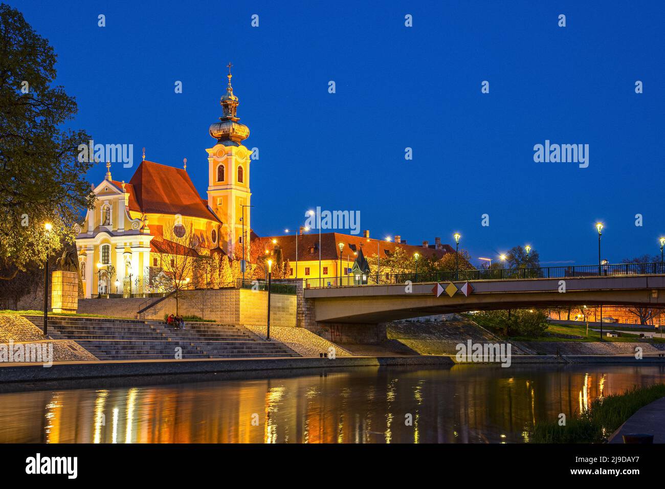 Gyor, ciudad de Hungría, iglesia carmelita barroca por la noche que se refleja en el río Raba Foto de stock