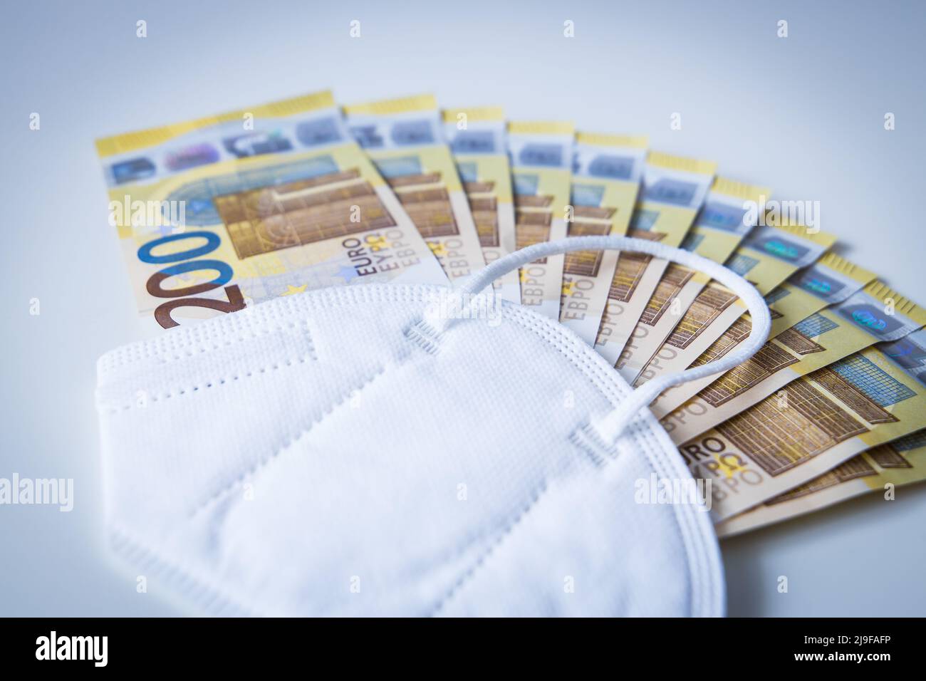 Mascarilla Corona con un paquete de billetes en euros Foto de stock