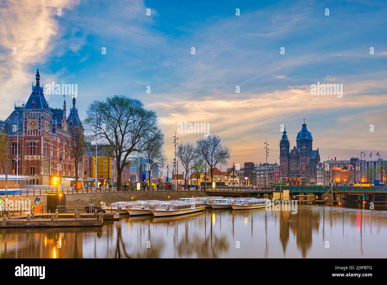 Ámsterdam Países Bajos, horizonte nocturno de la ciudad en la estación central de Ámsterdam y la Basílica de San Nicolás Foto de stock