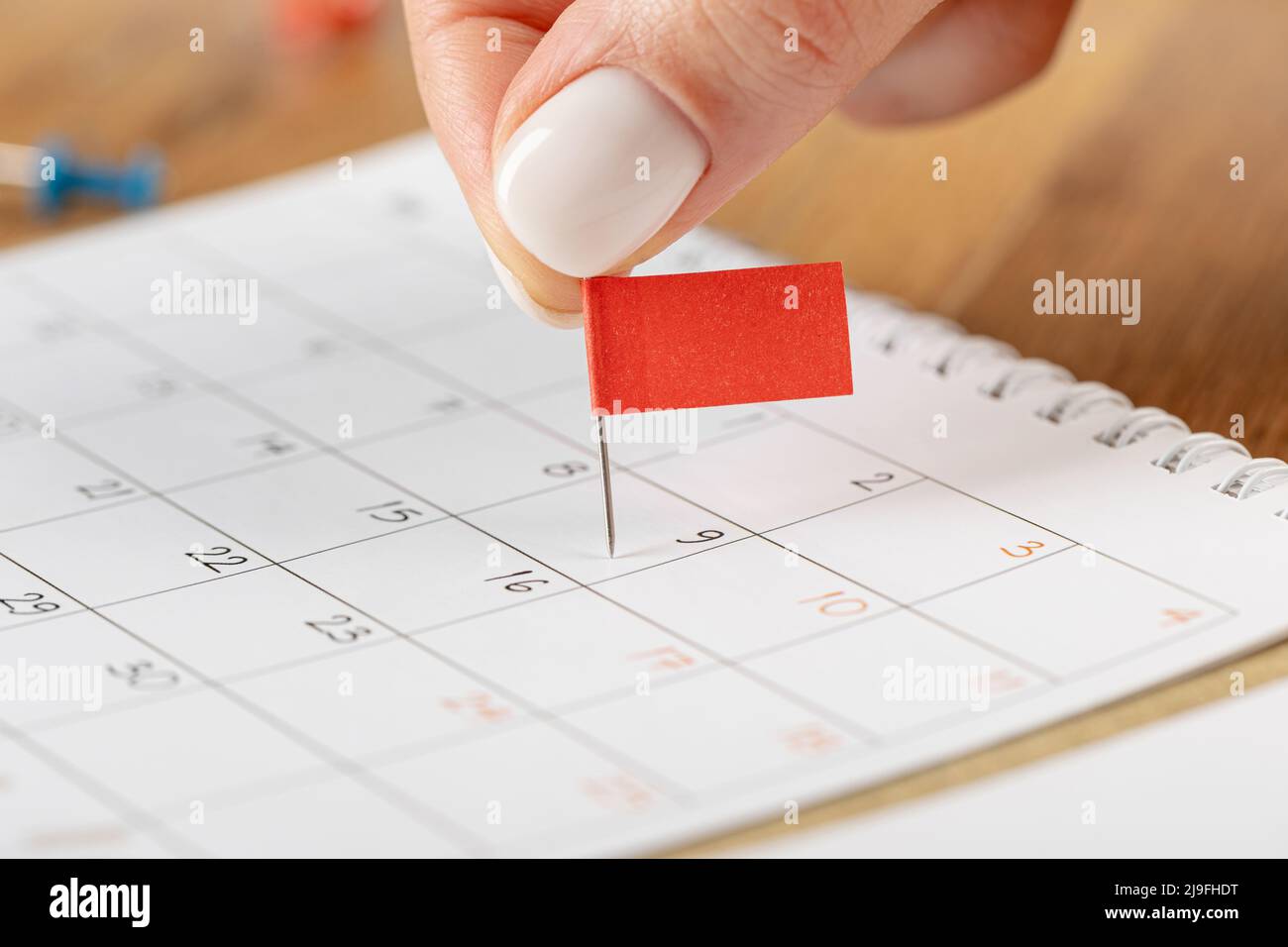 Programación de notas de fijación de manos, miniatura de pin de marca roja en el calendario para recordatorio de reunión y cita Foto de stock