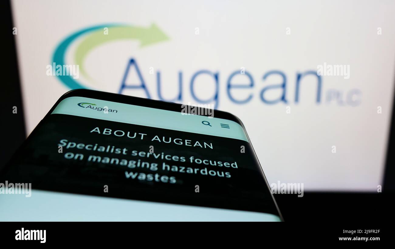 Teléfono móvil con sitio web de la empresa británica de gestión de residuos Augean plc en la pantalla frente al logotipo de la empresa. Enfoque en la parte superior izquierda de la pantalla del teléfono. Foto de stock