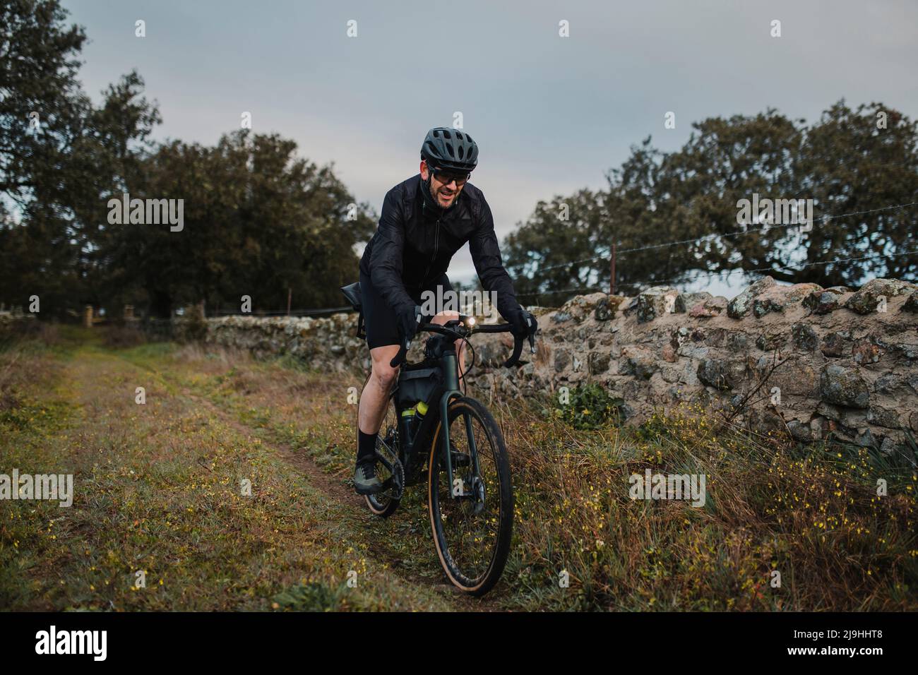 Un ciclista sonriente montando bicicleta por la pared Foto de stock