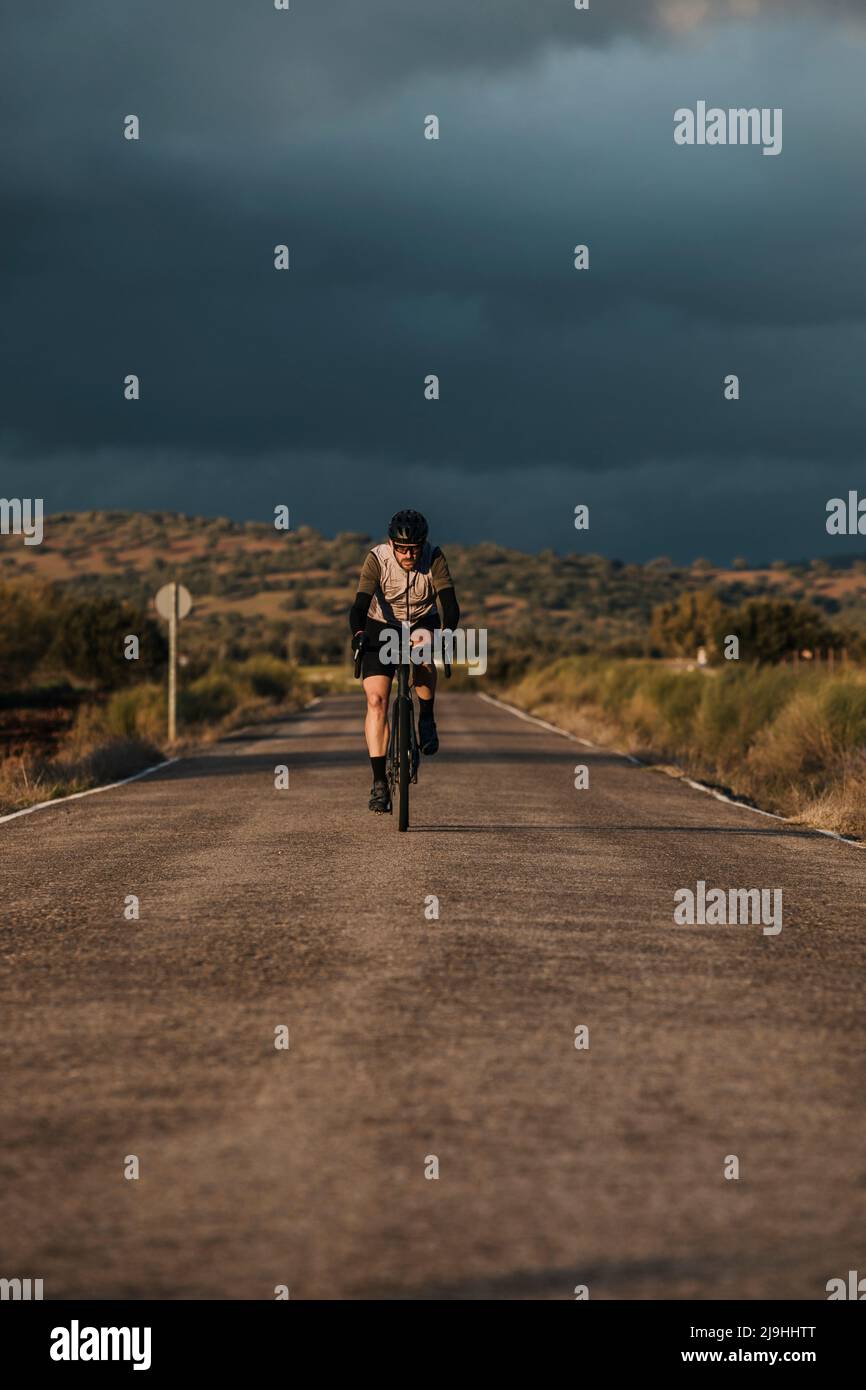 Ciclista montando en bicicleta por carretera al atardecer Foto de stock