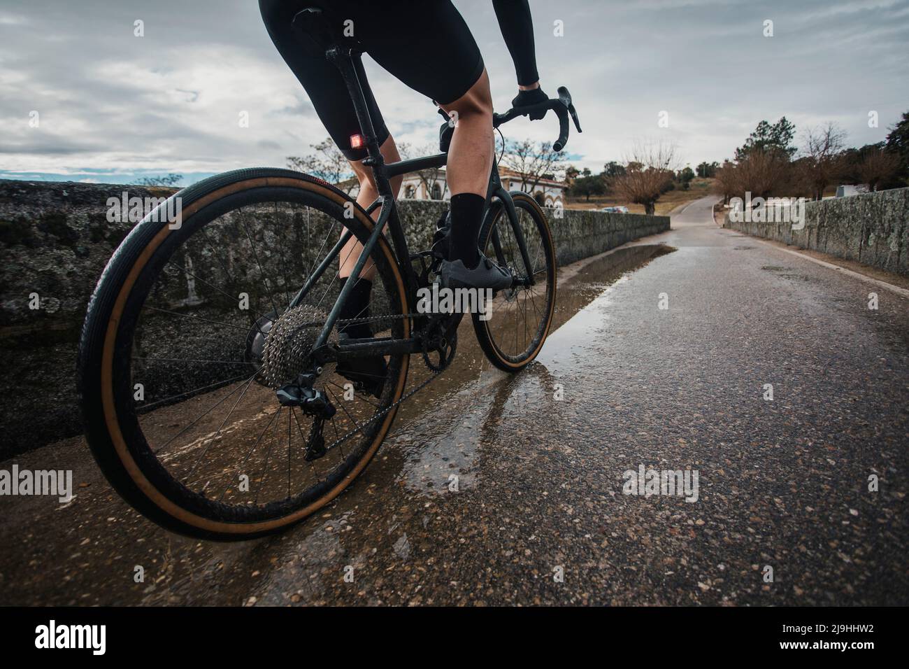 Ciclista montando en bicicleta en un puente húmedo Foto de stock