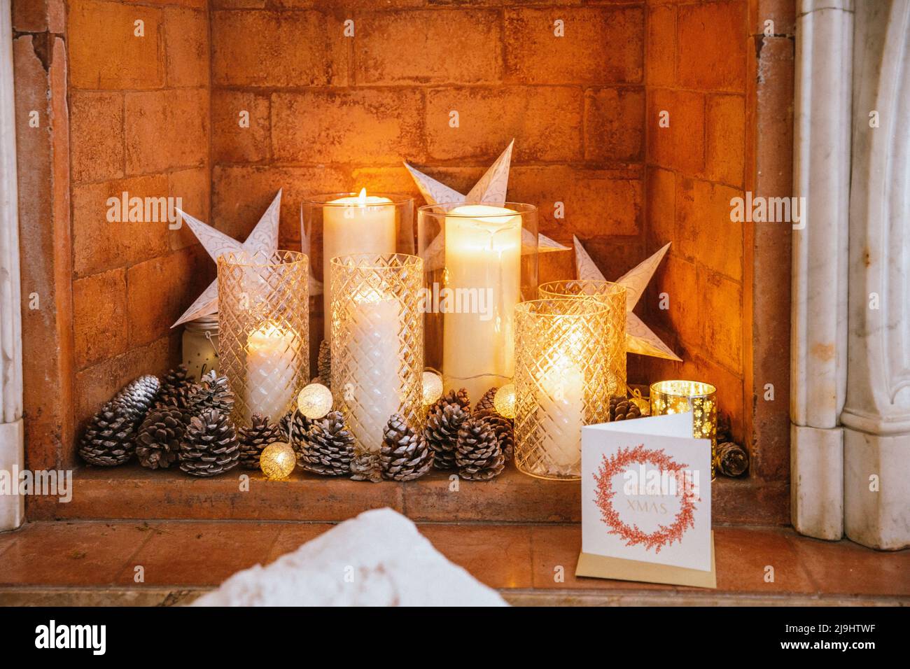 Velas de Navidad y tarjeta de felicitación dentro de la chimenea de ladrillo Foto de stock