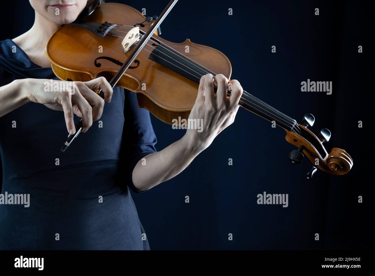 Mujer madura tocando violín frente a fondo negro Foto de stock