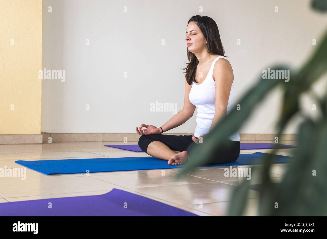 Mujer caucásica en una blusa blanca y licra negra practicando meditación en  una habitación Fotografía de stock - Alamy