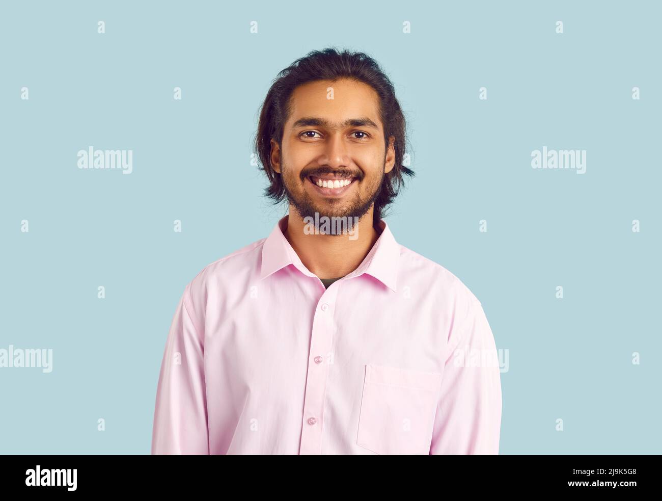 Retrato de un hombre indio feliz con una hermosa sonrisa blanca nieve sobre fondo azul claro pastel. Foto de stock