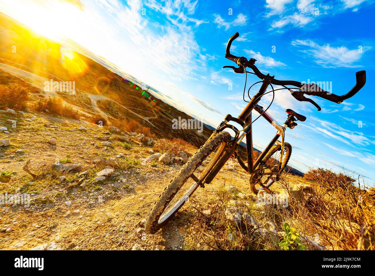 las bicicletas de montaña se inclinaron sobre una roca junto a un hermoso sendero cuesta abajo y paisaje al atardecer Foto de stock