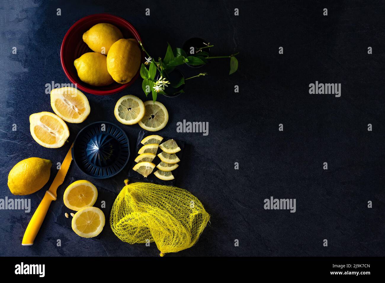 Elegante diseño de fondo de limones y rodajas de limón con exprimidor y cuchillo sobre cemento oscuro o negro o superficie de piedra. Foto de stock