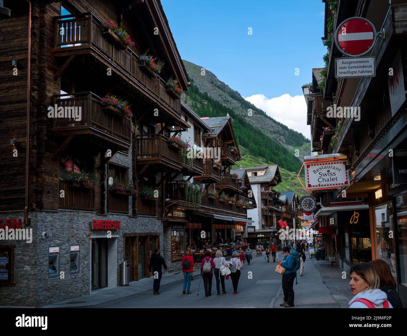 La pintoresca calle comercial principal de Zermatt con restaurantes, casas de campo locales, hoteles y tiendas llenas de turistas capturados en verano Foto de stock