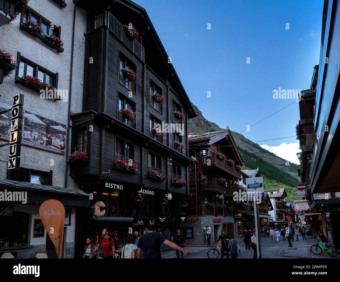 La pintoresca calle comercial principal de Zermatt con restaurantes, casas de campo locales, hoteles y tiendas llenas de turistas capturados en verano Foto de stock