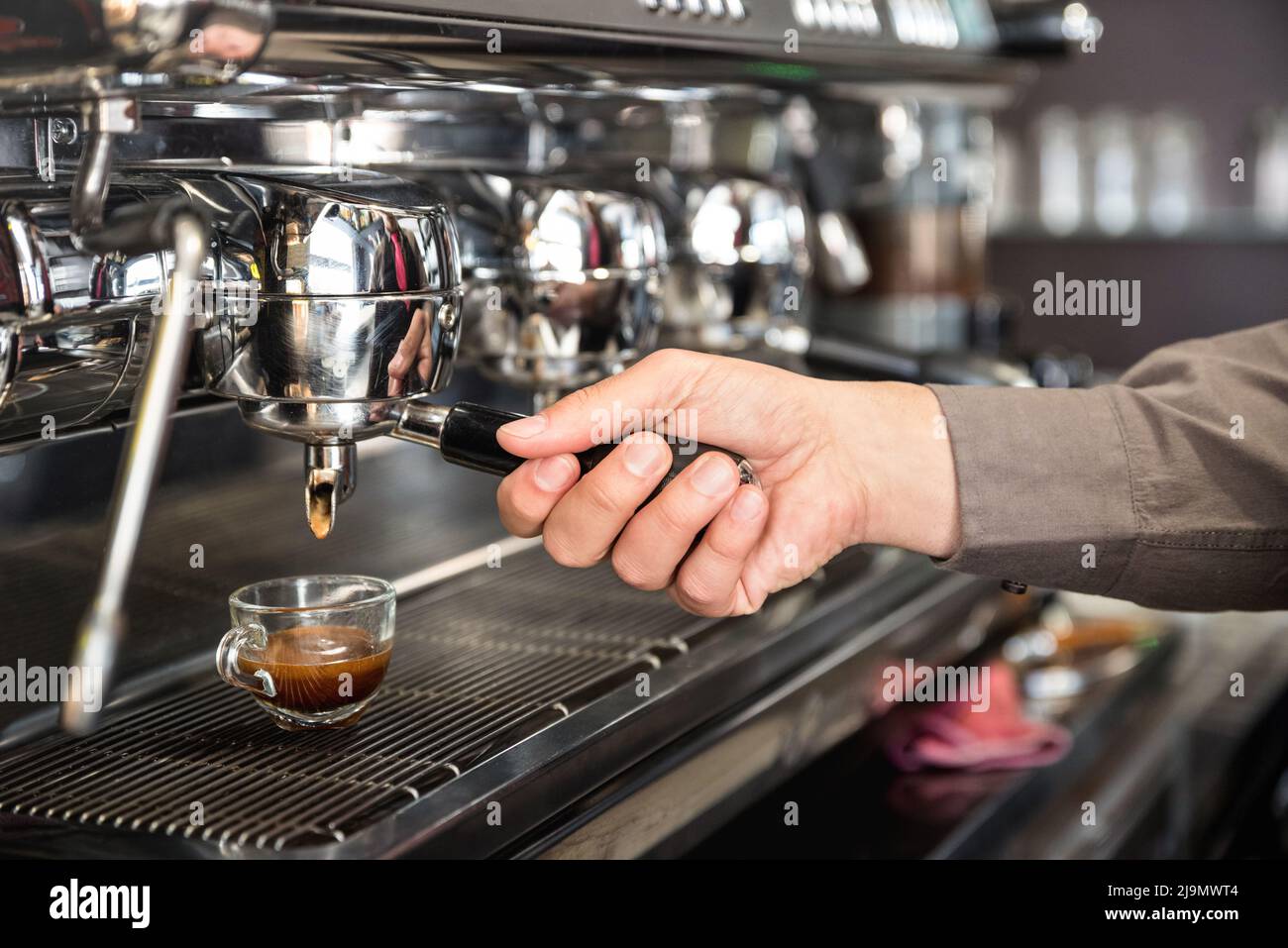 Barman clásico que prepara a mano espresso italiano en una moderna cafetera en la cafetería de moda - Concepto de comida y bebida con bartend profesional Foto de stock