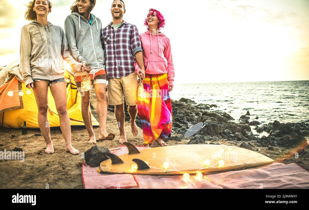 Amigos hipster divertirse caminando con linternas de neón led en la fiesta de camping en la playa - concepto de viaje de amistad con gente joven vagabundos relajándose en su Foto de stock