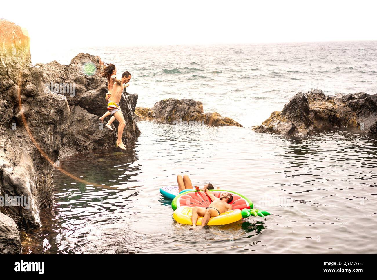Amigos locos vacacionistas saltando en la piscina natural en la ubicación de la playa de viaje - Jóvenes divirtiéndose buceando en el mar salvaje - Conc estilo de vida Wanderlust Foto de stock