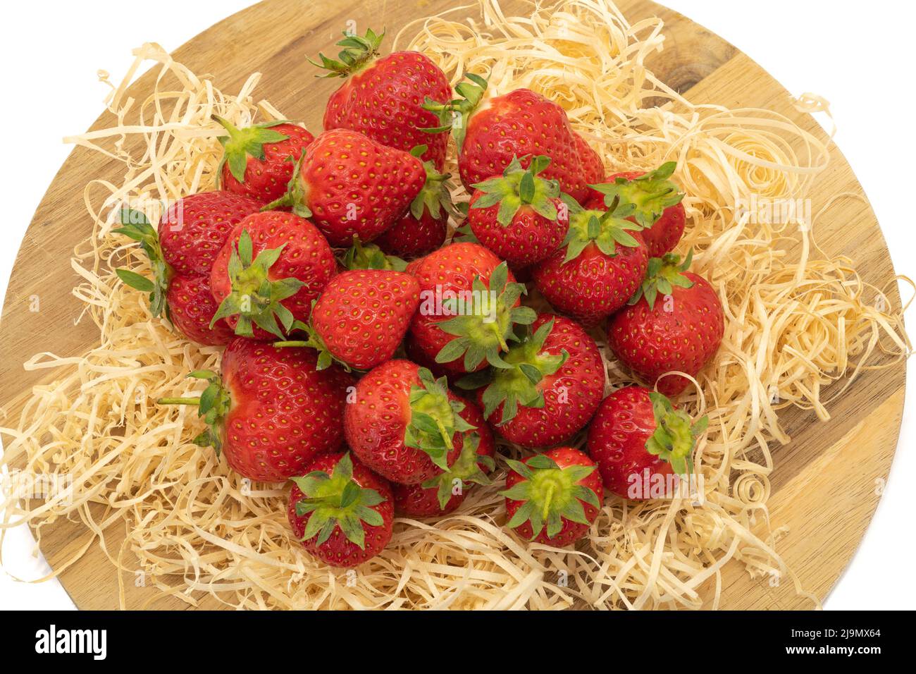 Un lote de fresas frescas tumbadas sobre paja fresca del jardín y listas para comer Foto de stock