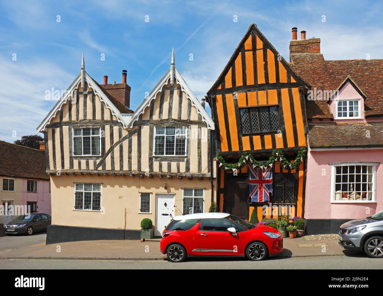 Una vista de la Crooked House, una casa histórica de entramado de madera de color naranja en el pueblo medieval de Lavenham, Suffolk, Inglaterra, Reino Unido. Foto de stock