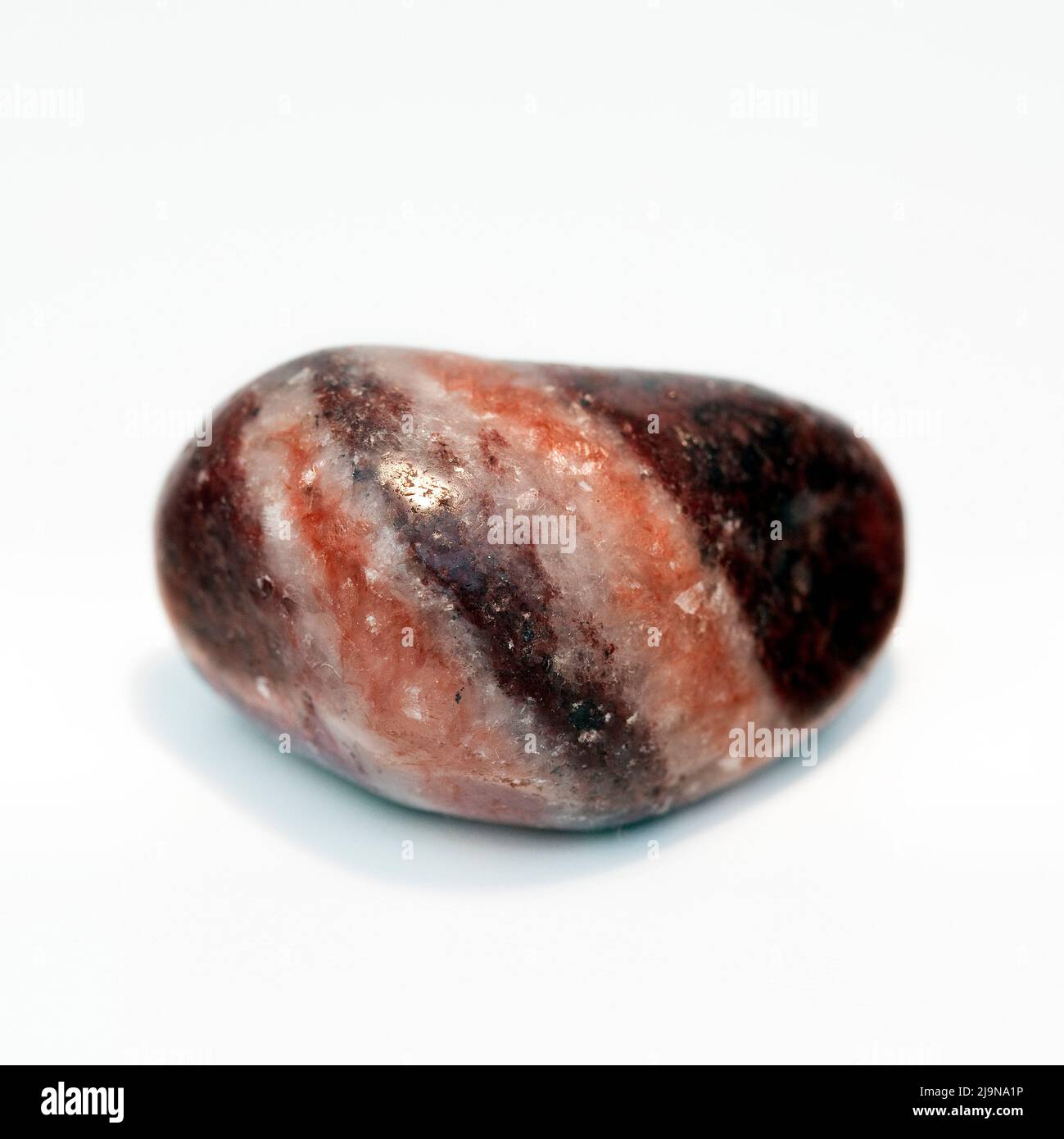Macro tomó una fotografía en color de primer plano de una 'Magnesita Roja' pulida, una piedra curativa semipreciosa de cristal Foto de stock