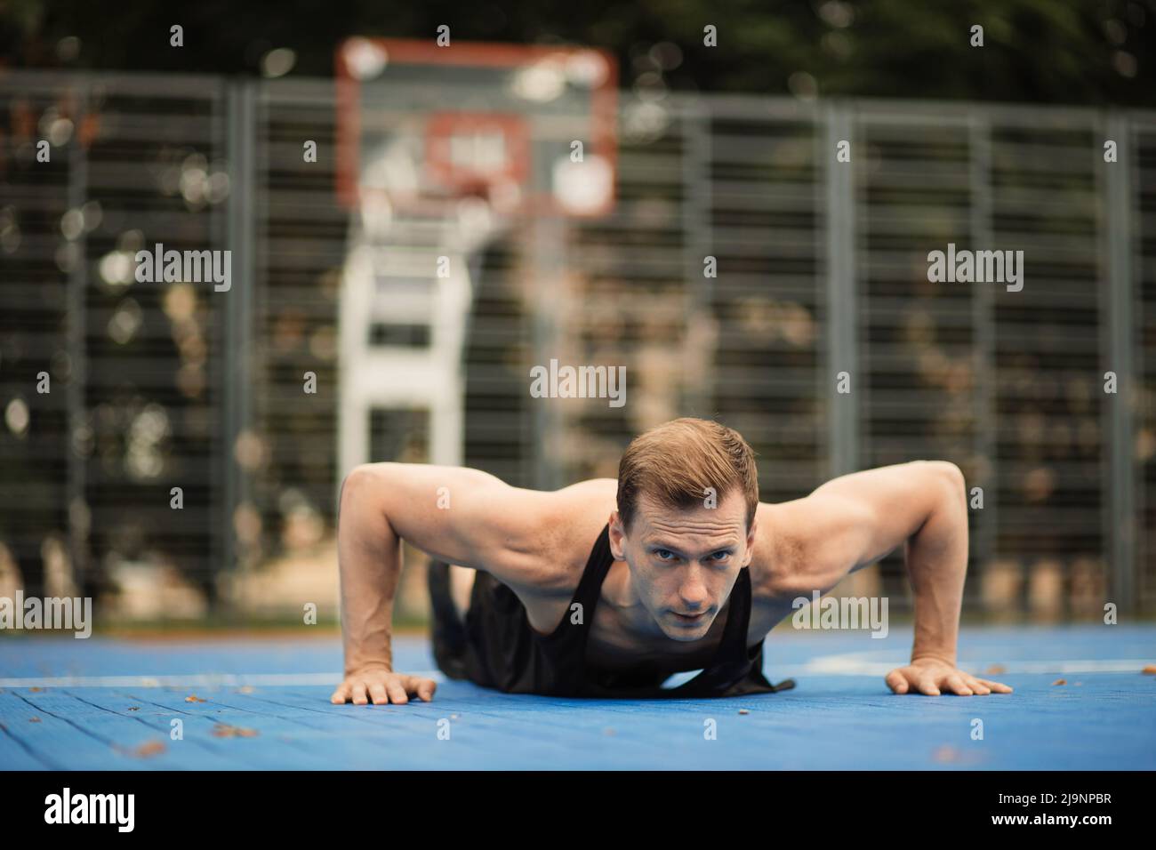 Monte a un joven caucásico haciendo ejercicio en el entrenamiento crossfit  de resistencia haciendo flexiones en el parque calistenico. Hombre de pie  en posición de plancha sobre la alfombra. Concepto de salud,