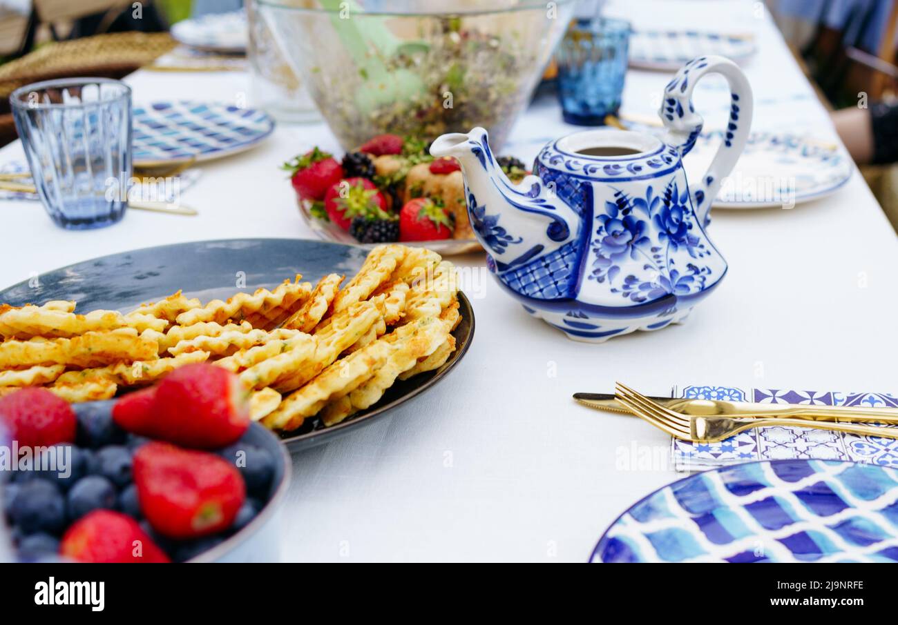 Gofres con bayas en la mesa festiva de fin de semana de verano en estilo azul Foto de stock