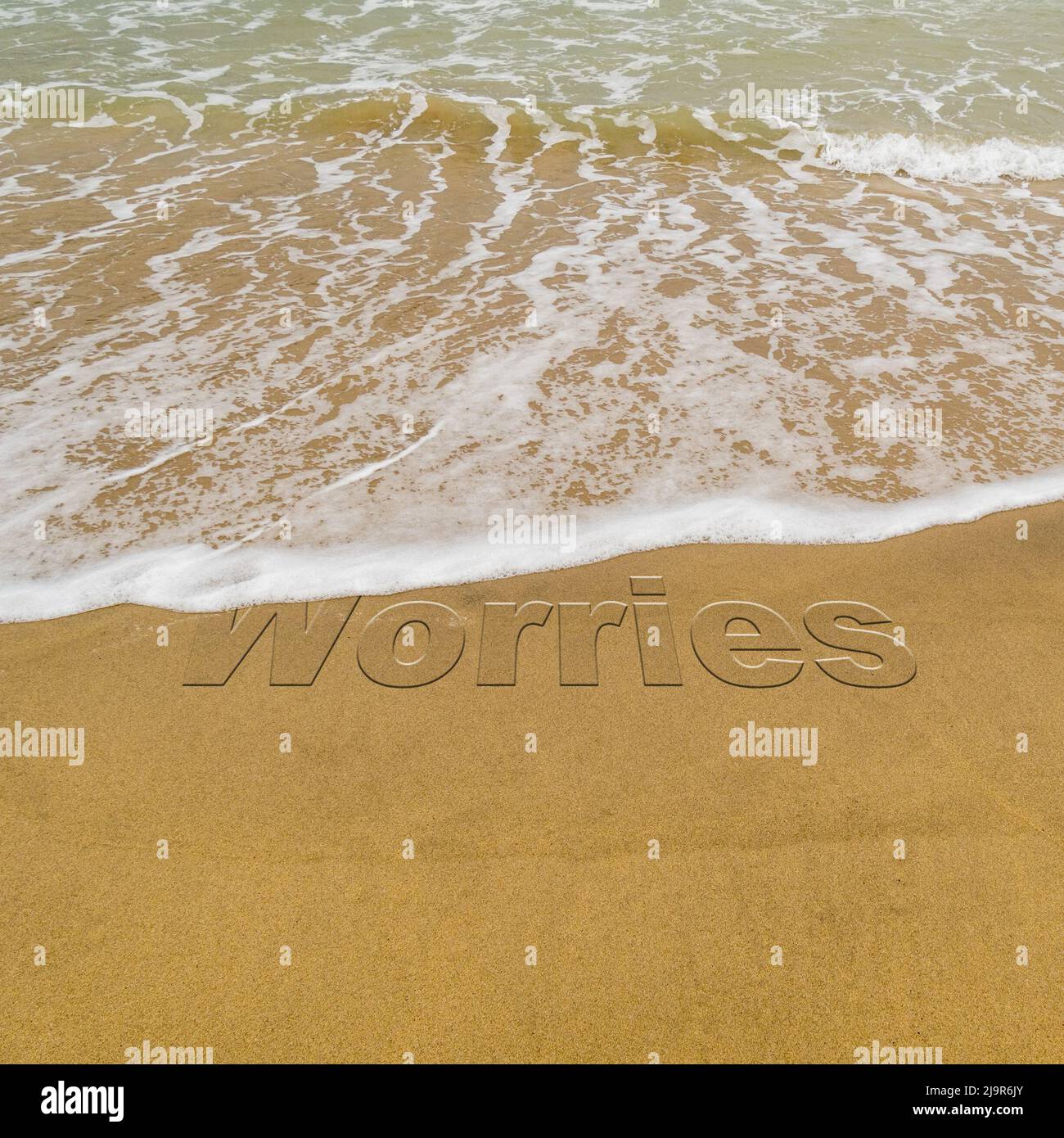 Imagen conceptual: Para ilustrar el lavado del estrés tomando unas vacaciones mientras las olas en una playa de arena lavan la palabra 'preocupaciones'. Foto de stock