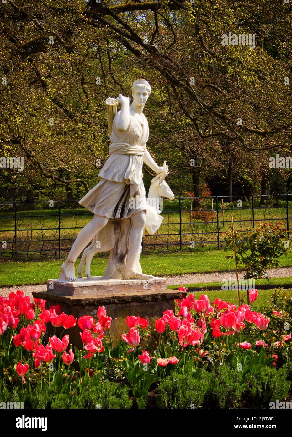 Una estatua en los terrenos de Lytham Hall, rodeada de flores de primavera Foto de stock