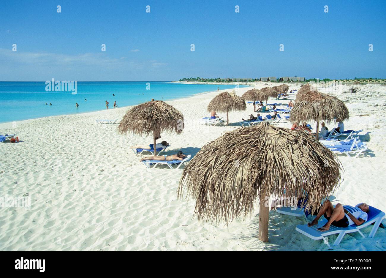 Touristen unter Sonnenschutzschirmen am Strand bei Cayo Largo, Kuba, Karibik | Turistas bajo sombrillas en la playa de Cayo Largo, Cuba, Caribb Foto de stock