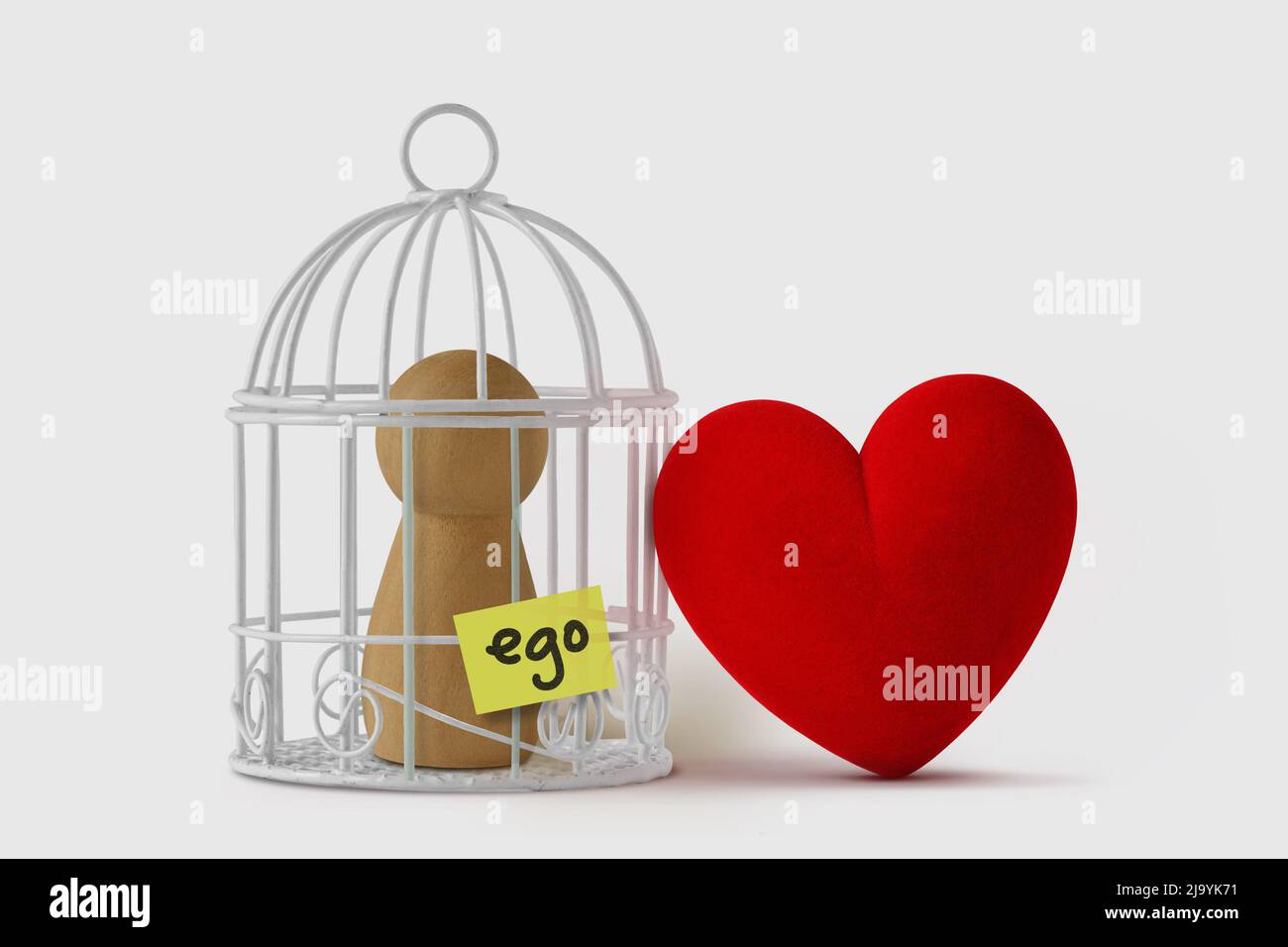 Peón en una jaula de pájaros con la palabra Ego escrito en nota de papel y corazón libre - concepto de amor y ego Foto de stock
