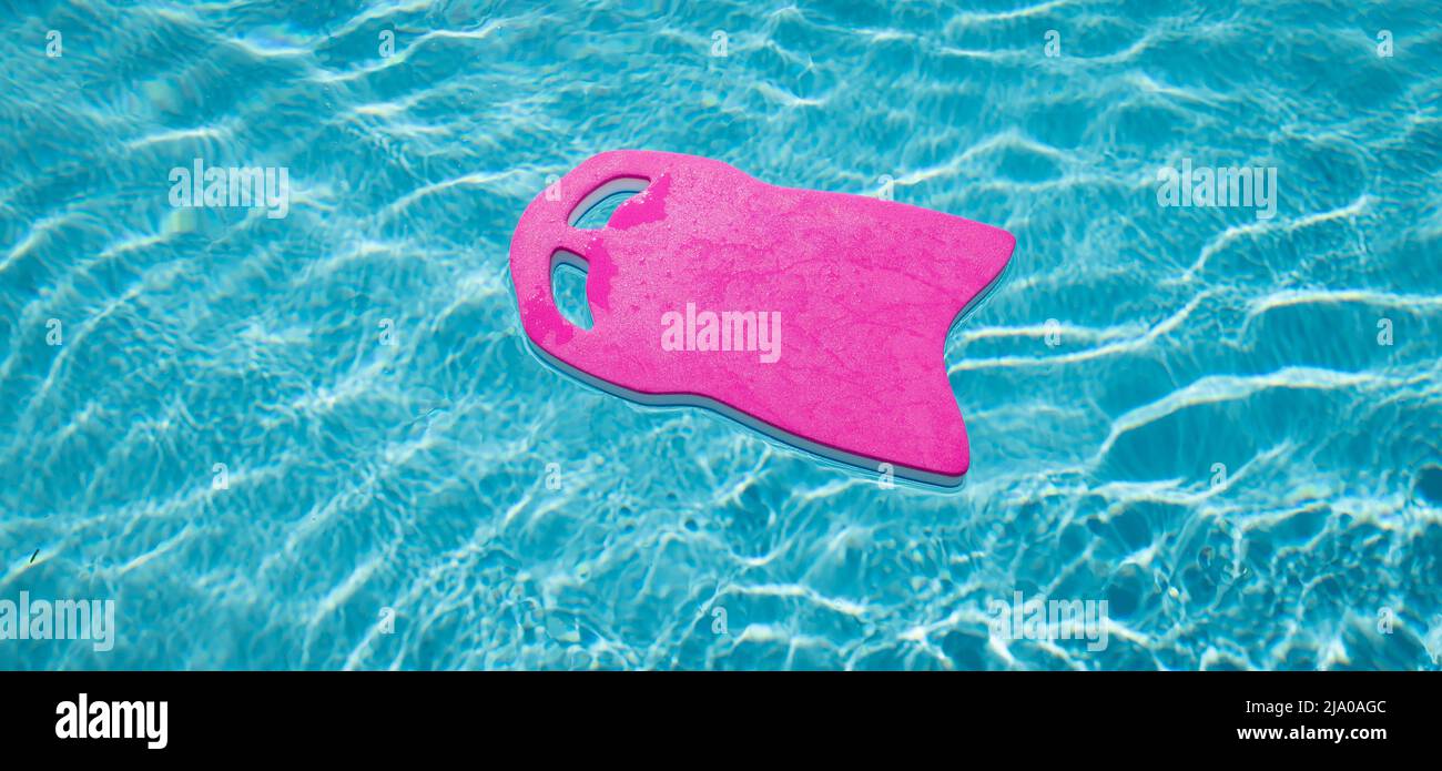 Tablero de espuma rosa flotando en la piscina. Foto de stock