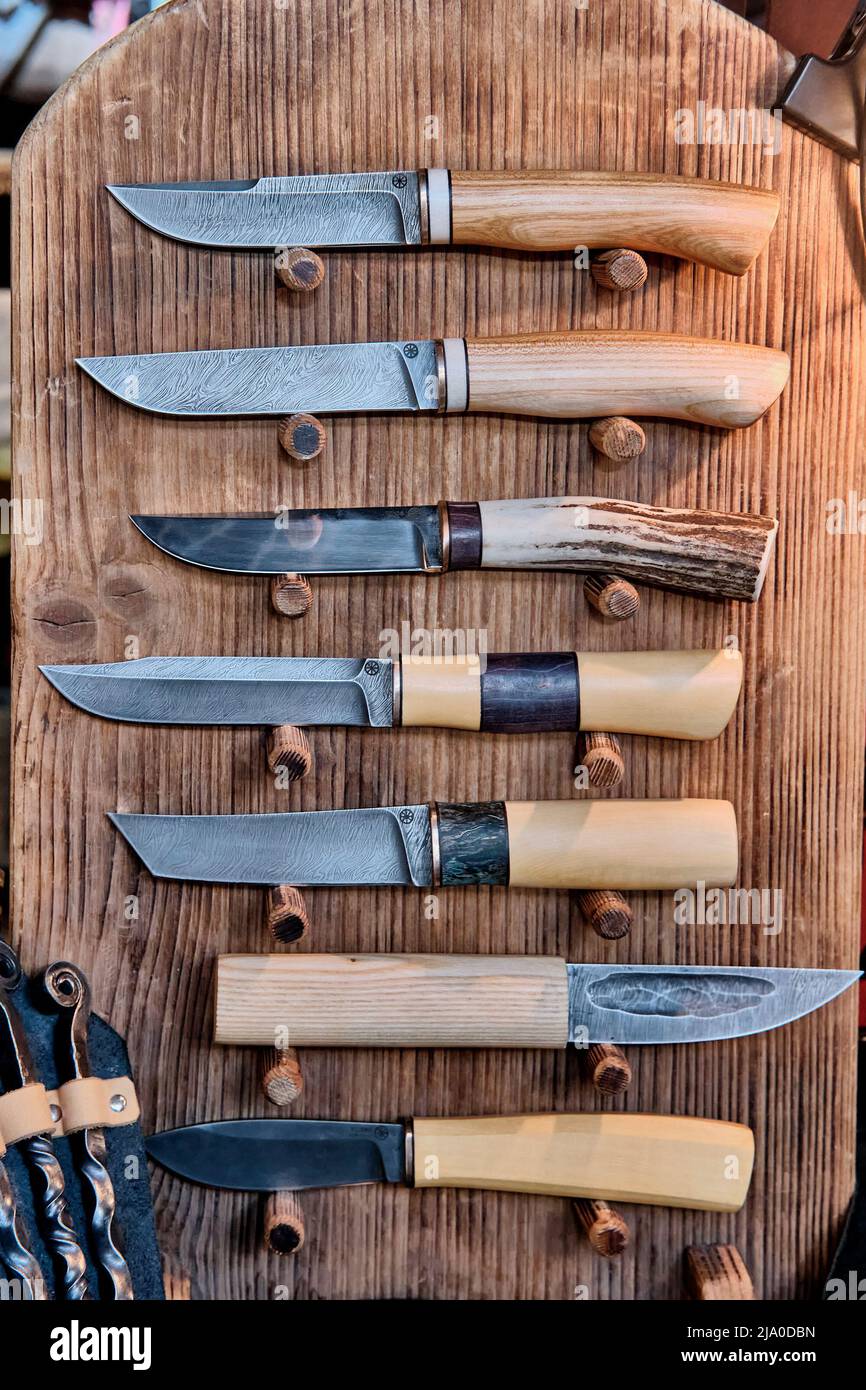 Varios cuchillos caseros o de caza hechos a mano con mangos de madera sobre  tablas de madera Fotografía de stock - Alamy