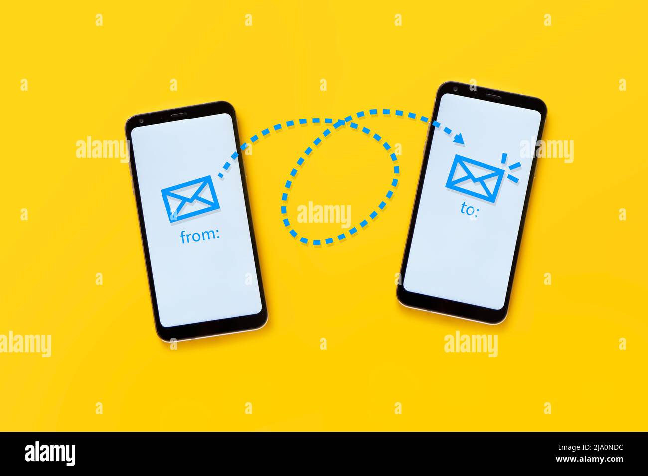 concepto de correo electrónico. Dos teléfonos móviles sobre fondo amarillo que muestran el funcionamiento del correo electrónico a través de un dibujo. Foto de stock