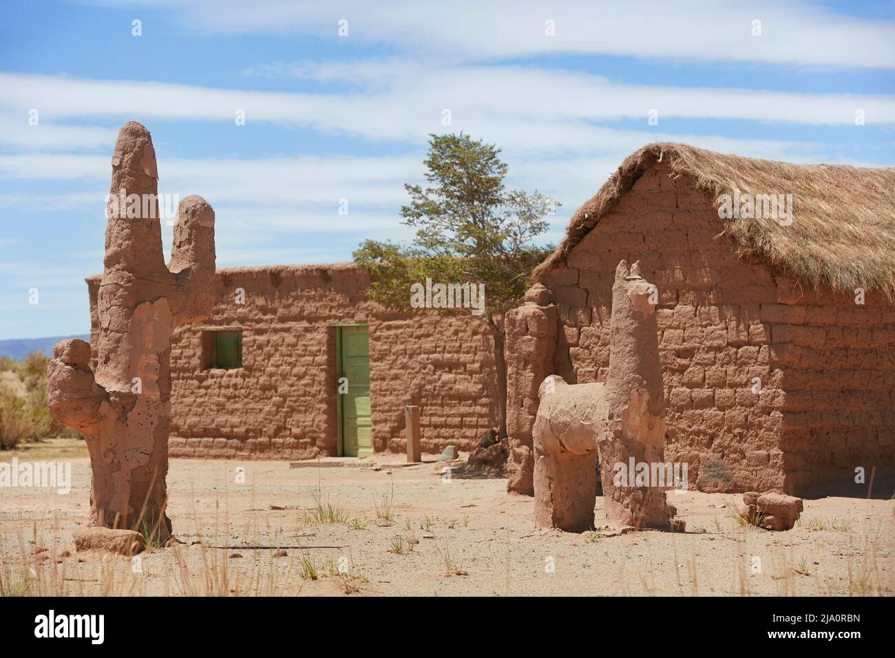 Casa tradicional de barro con esculturas de llama y cactus. Santuario Tres Pozos, cerca de las Salinas Grandes, provincia de Jujuy, Argentina. Foto de stock