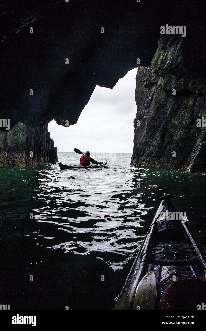 Kayak de mar explorando una cueva en Anglesey, Gales del Norte Foto de stock