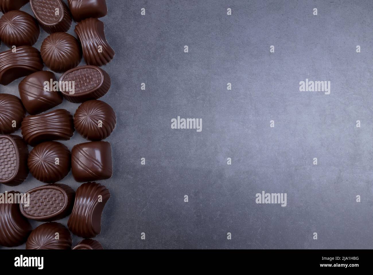 Pralinés variados de chocolate negro sobre fondo negro. Chocolate amoroso y dulces concepto Foto de stock