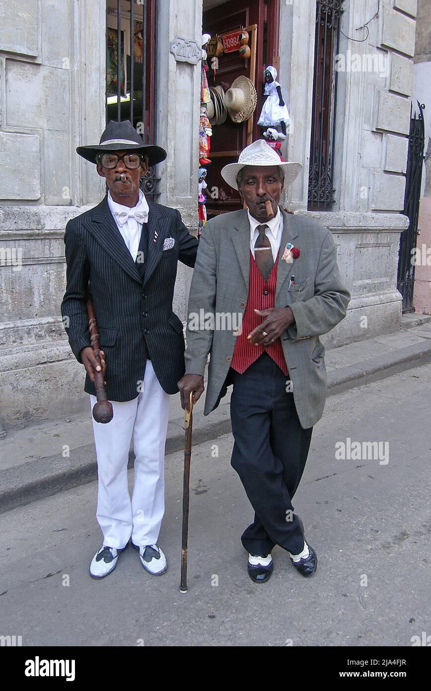 Dos hombres cubanos bien vestidos, fumadores de cigarros, Cathedral Plaza, casco antiguo histórico de La Habana, Cuba, Caribe Foto de stock