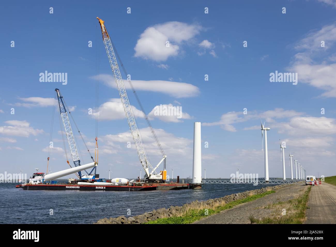 Lelystad, Países Bajos - 22 de abril de 2022: Grúa y buque de suministro ocupado con la demolición de la antigua turbina eólica marina Foto de stock