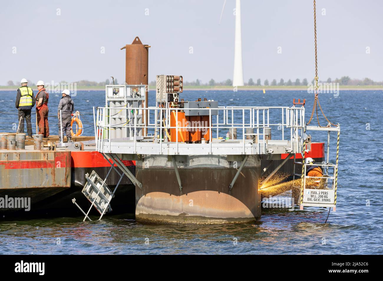 Lelystad, Países Bajos - 22 de abril de 2022: Trabajador con antorcha de corte en el trabajo por la fundación de demolición aerogenerador offshore Foto de stock