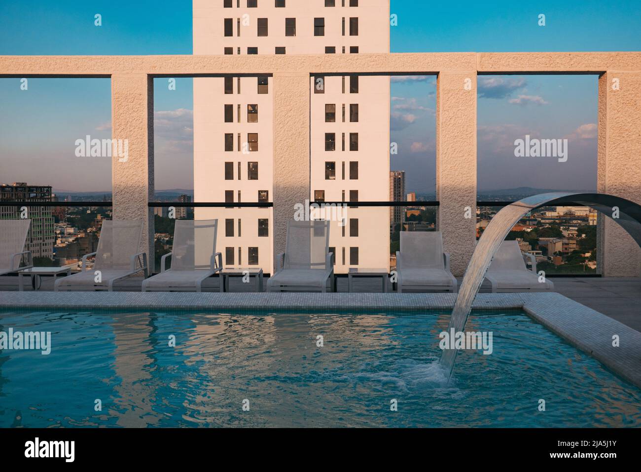 El sol matutino proyecta sombras en los pilares de una piscina en la azotea de un moderno apartamento en la ciudad de Guadalajara, México Foto de stock
