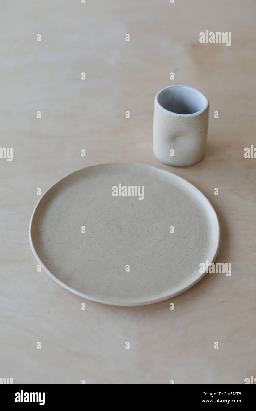 copa y platos de cerámica en una mesa de madera vista. conjunto minimalista de cerámica hecha a mano vajilla y cerámica Foto de stock