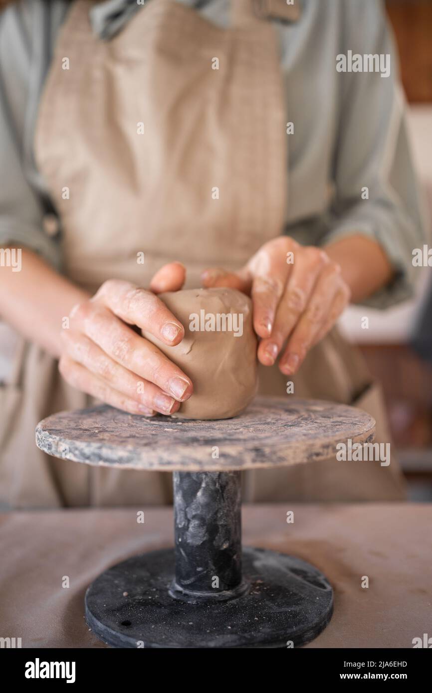 Proceso creativo de artesanía artista mujer utiliza herramienta para dar forma y esculpir a mano alfarería. Mesa de trabajo en un taller donde un alfarero trabaja con crudo Foto de stock