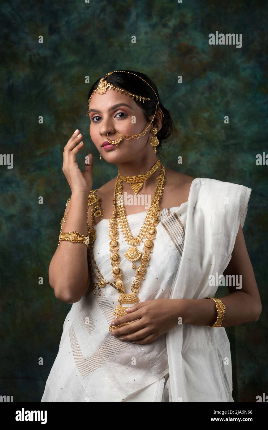 Modelo hembra india que lleva un saree blanco y joyas de oro que luce