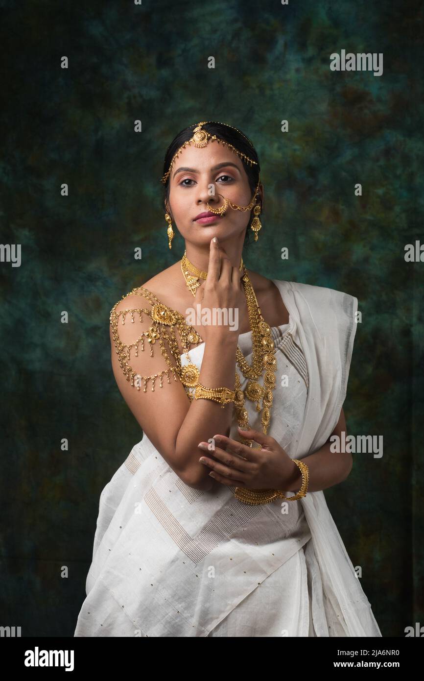 Modelo hembra india que lleva un saree blanco y joyas de oro que luce