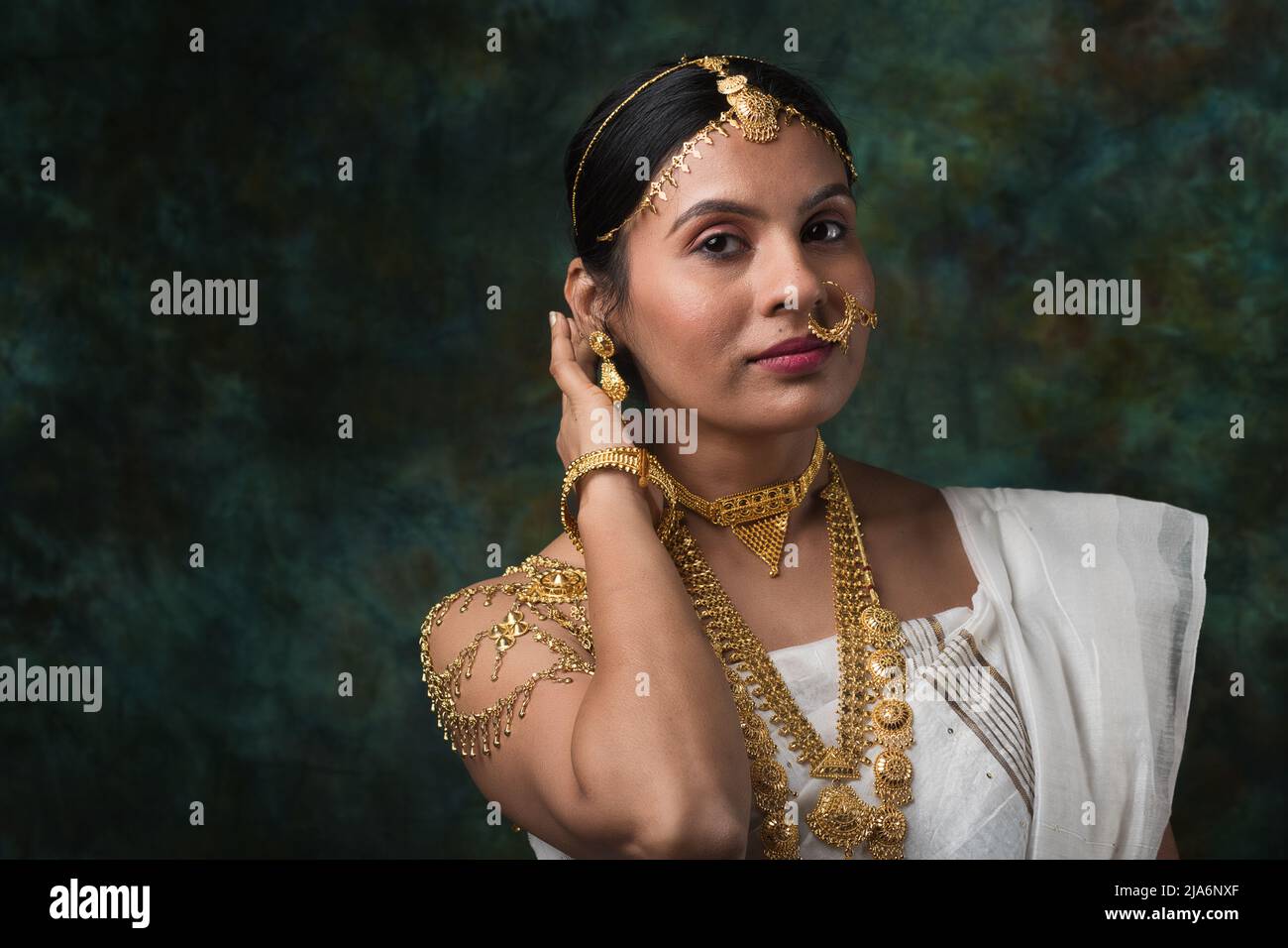 Modelo hembra india que lleva un saree blanco y joyas de oro que luce