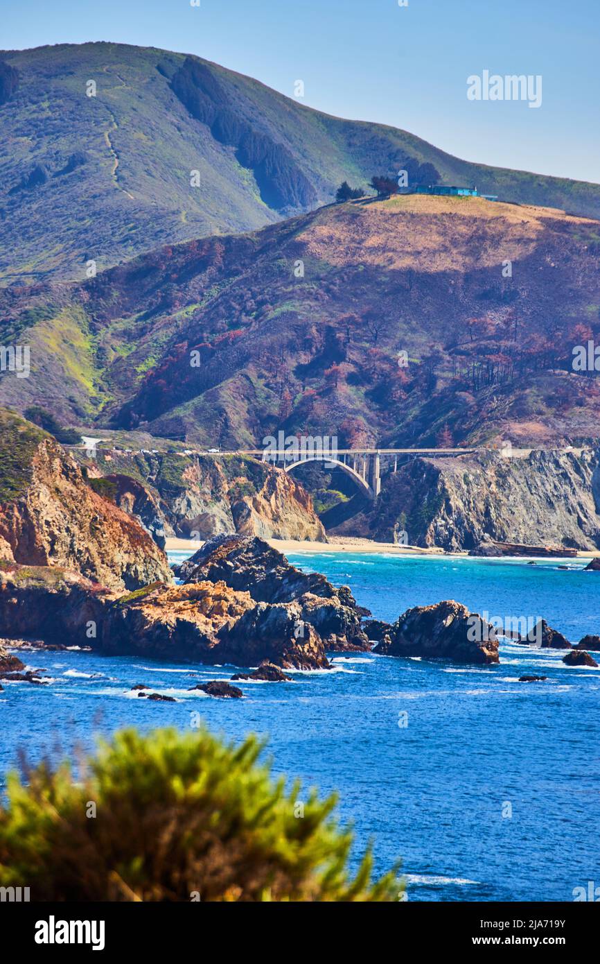 Puente Bixby vertical sobre el océano desde la distancia rodeada de montañas Foto de stock