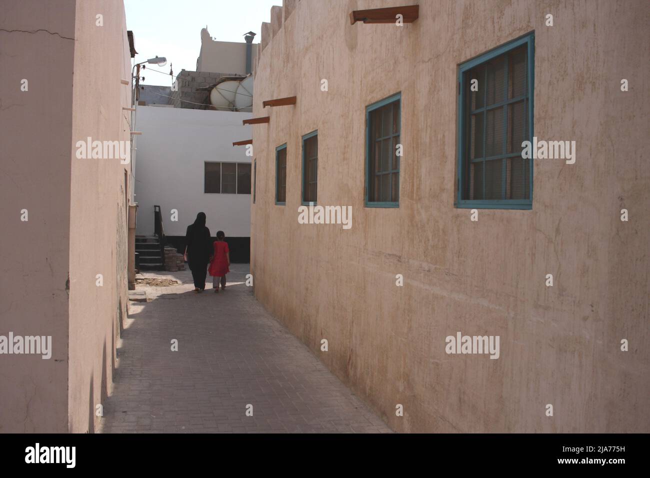 Una mujer y un niño de Bahrein caminando a lo largo de un estrecho callejón en el Camino de las Perlas, Muharraq, Reino de Bahrein Foto de stock