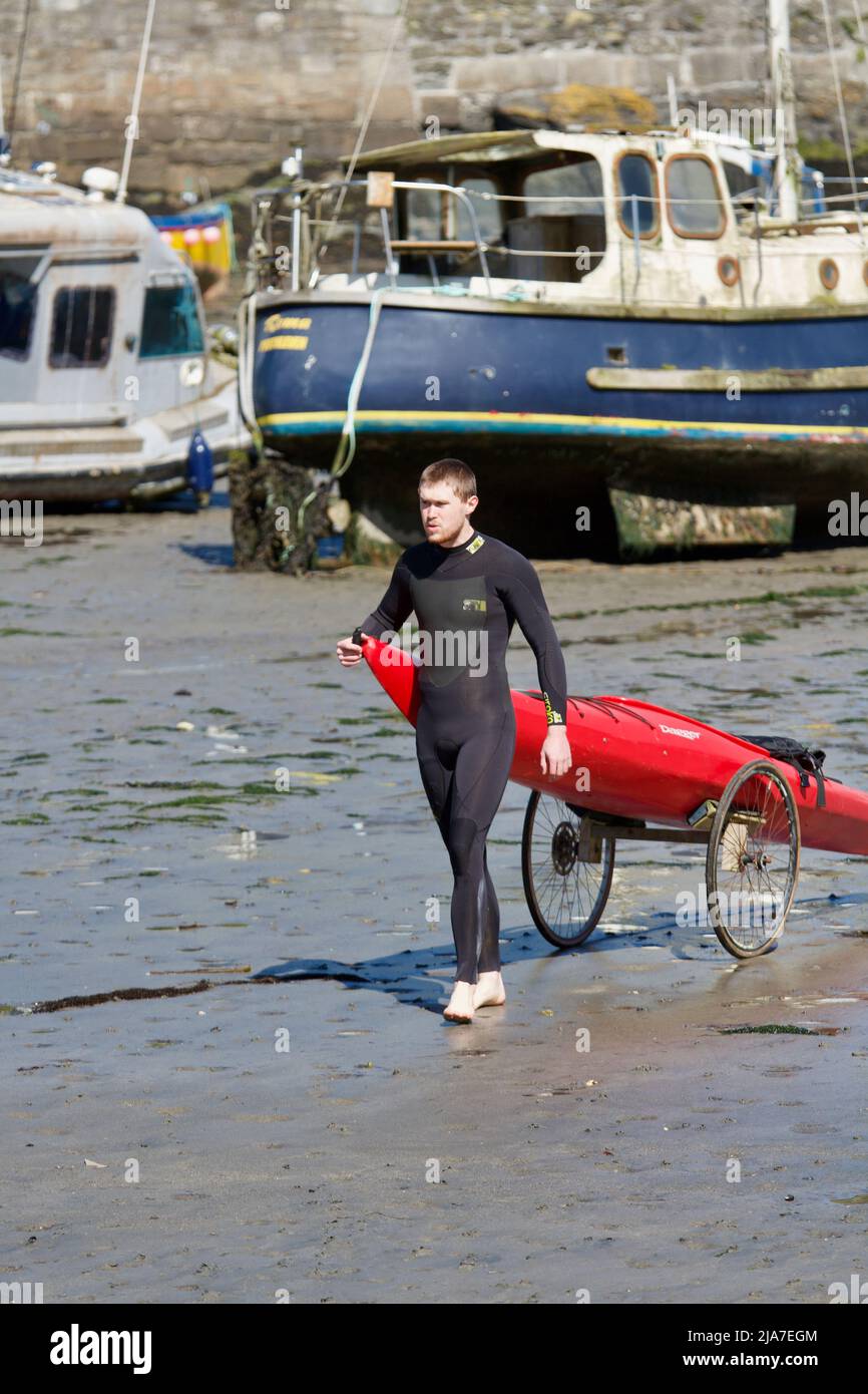 Hombre joven en traje de neopreno con su kayak en un tranvía en el