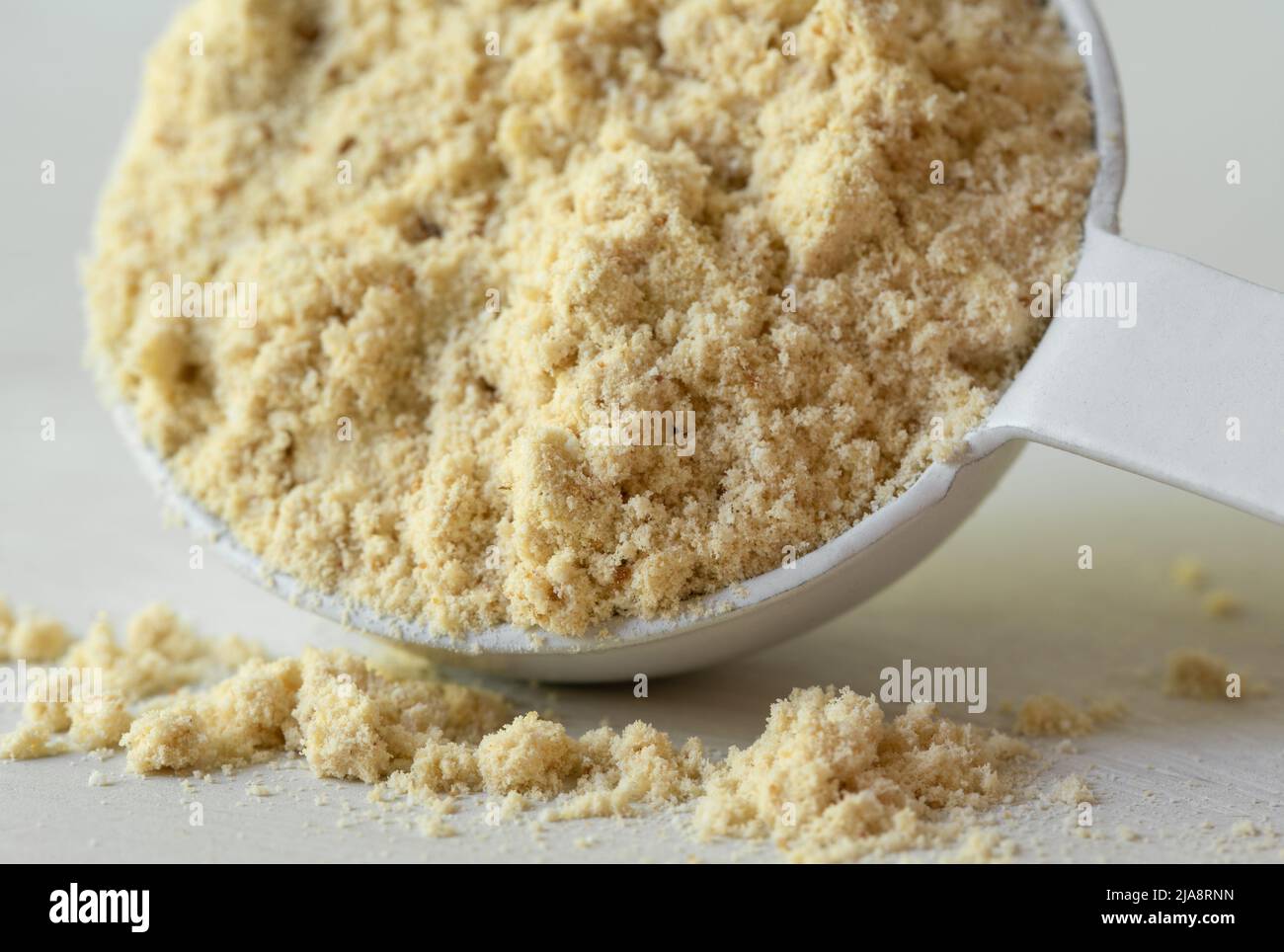 Polvo de proteína de vainilla derramado de una cucharadita Foto de stock